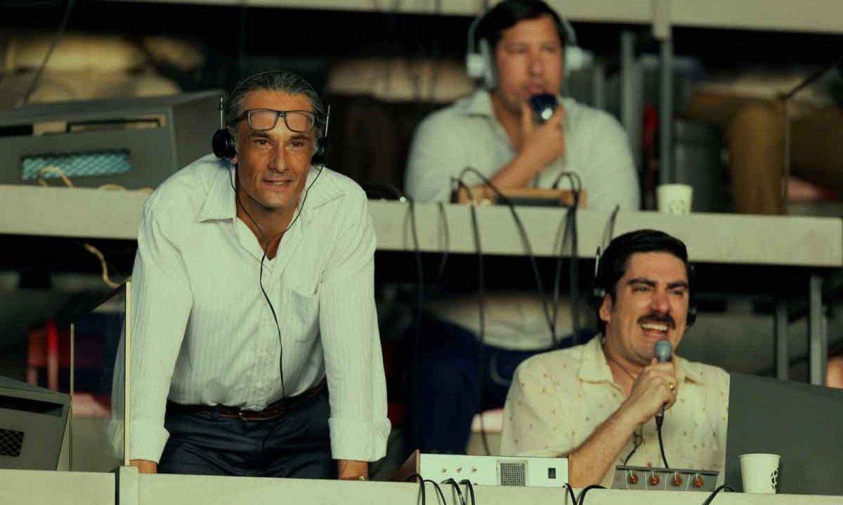 Rodrigo Santoro como o t&eacute;cnico de futebol Jo&atilde;o Saldanha est&aacute; na cabine de radialistas durante jogo em cena da s&eacute;rie  Brasil 70 &ndash; A saga do tri