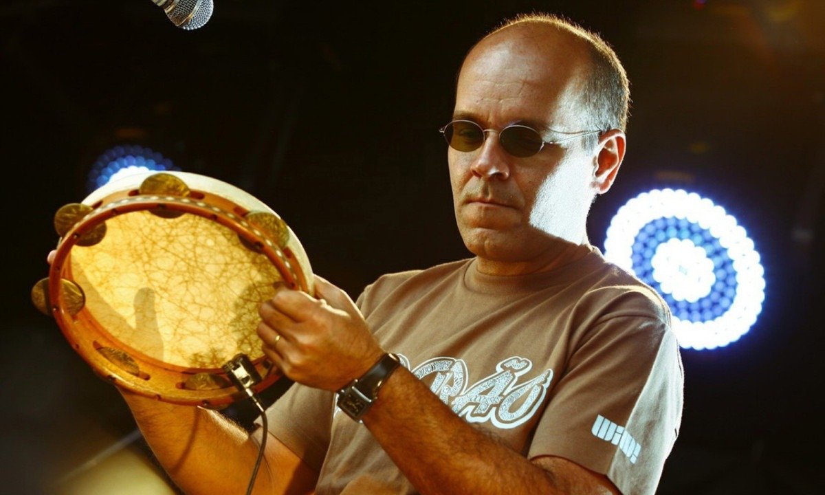 Marcos Suzano toca pandeiro em frente ao microfone durante show  