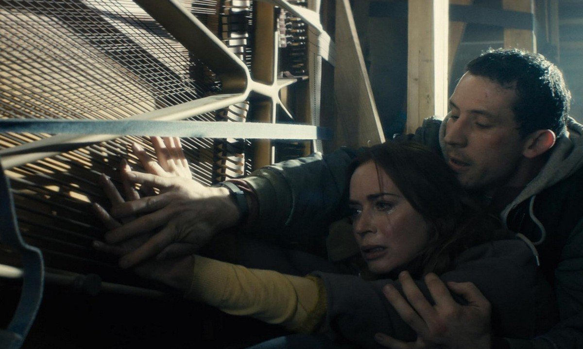 Atriz Emily Blunt, &agrave;s l&aacute;grimas, e o ator Josh O'Connor empurram imensa estrutura met&aacute;lica em cena do filme Dia D, sobre a presen&ccedil;a de ETs na Terra