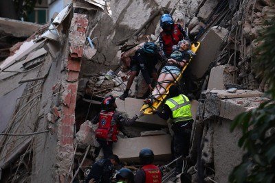  TOPSHOT - Rescue workers carry a person on a stretcher out of a collapsed building following an earthquake in Caracas on June 24, 2026. A magnitude 7.1 earthquake struck Venezuela on Wednesday, the United States Geological Survey (USGS) reported, triggering panic in Caracas, according to AFP journalists. The tremor, which was followed by several aftershocks, was also felt in Colombia. (Photo by Juan BARRETO / AFP)
      Caption  -  (crédito: Juan BARRETO / AFP)