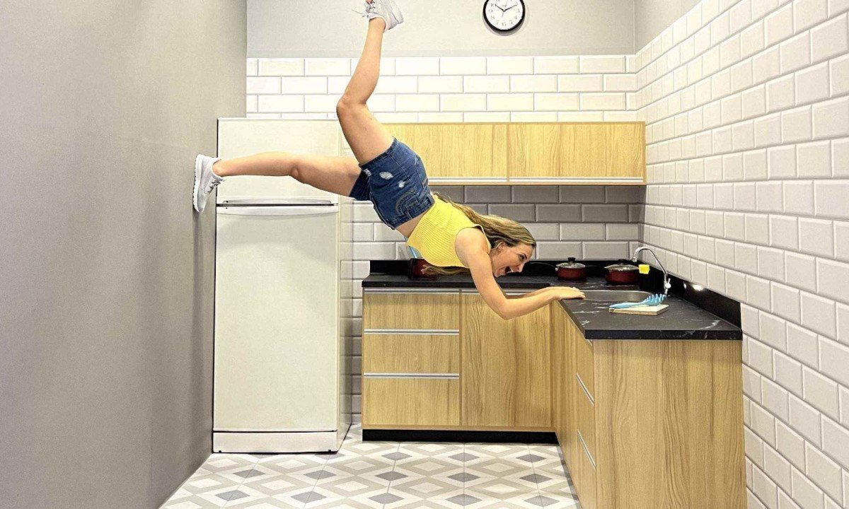 Mulher est&aacute; flutuando dentro de cozinha e tenta se segurar na quina da pia