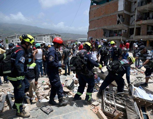  Members of search and rescue teams carry equipment across the rubble of damaged buildings in Catia La Mar, La Guaira, Venezuela, on June 26, 2026, following deadly earthquakes. The death toll from two powerful earthquakes that devastated Venezuela earlier this week rose to 920 on June 26, National Assembly President Jorge Rodriguez said. (Photo by Federico PARRA / AFP)
       -  (crédito:  AFP)