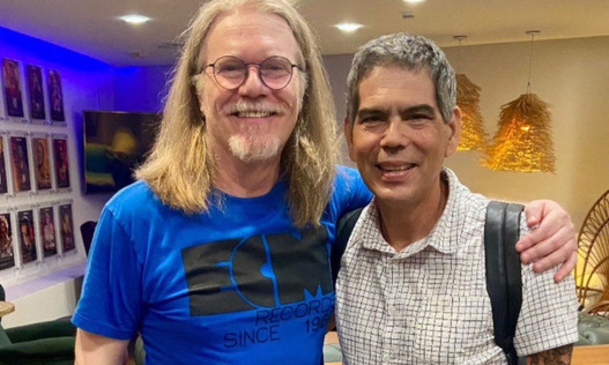 Humberto Gessinger e Dado Villa-Lobos est&atilde;o abra&ccedil;ados e sorriem para a c&acirc;mera