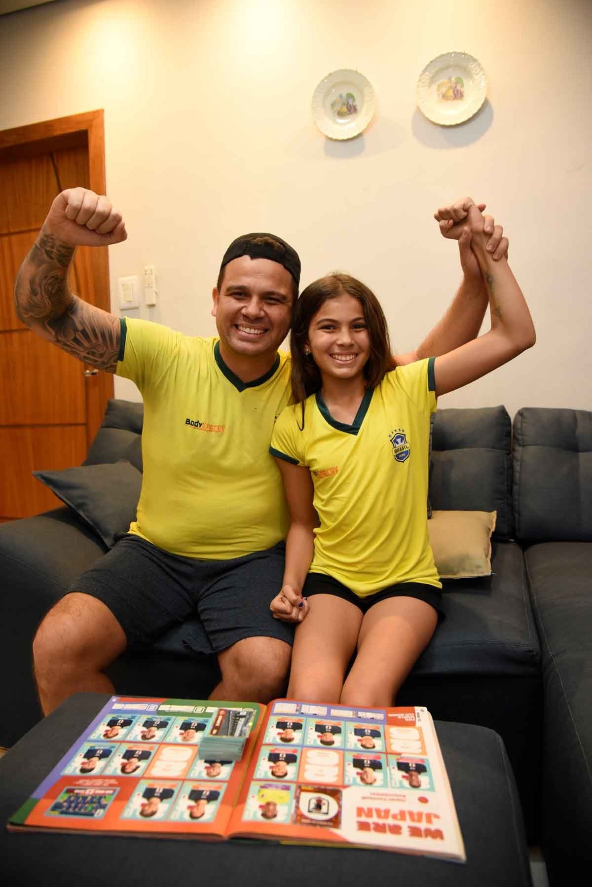 Felipe e a filha Sofia colando figurinha no &aacute;lbum  