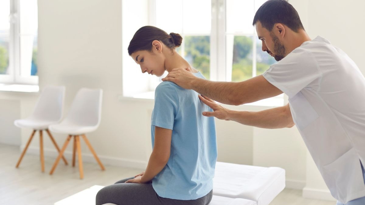 Profissional de sa&uacute;de avalia a coluna de uma jovem, refor&ccedil;ando a import&acirc;ncia do exame f&iacute;sico para o diagn&oacute;stico precoce de escoliose em adolescentes. -  (crédito: studioroman)
