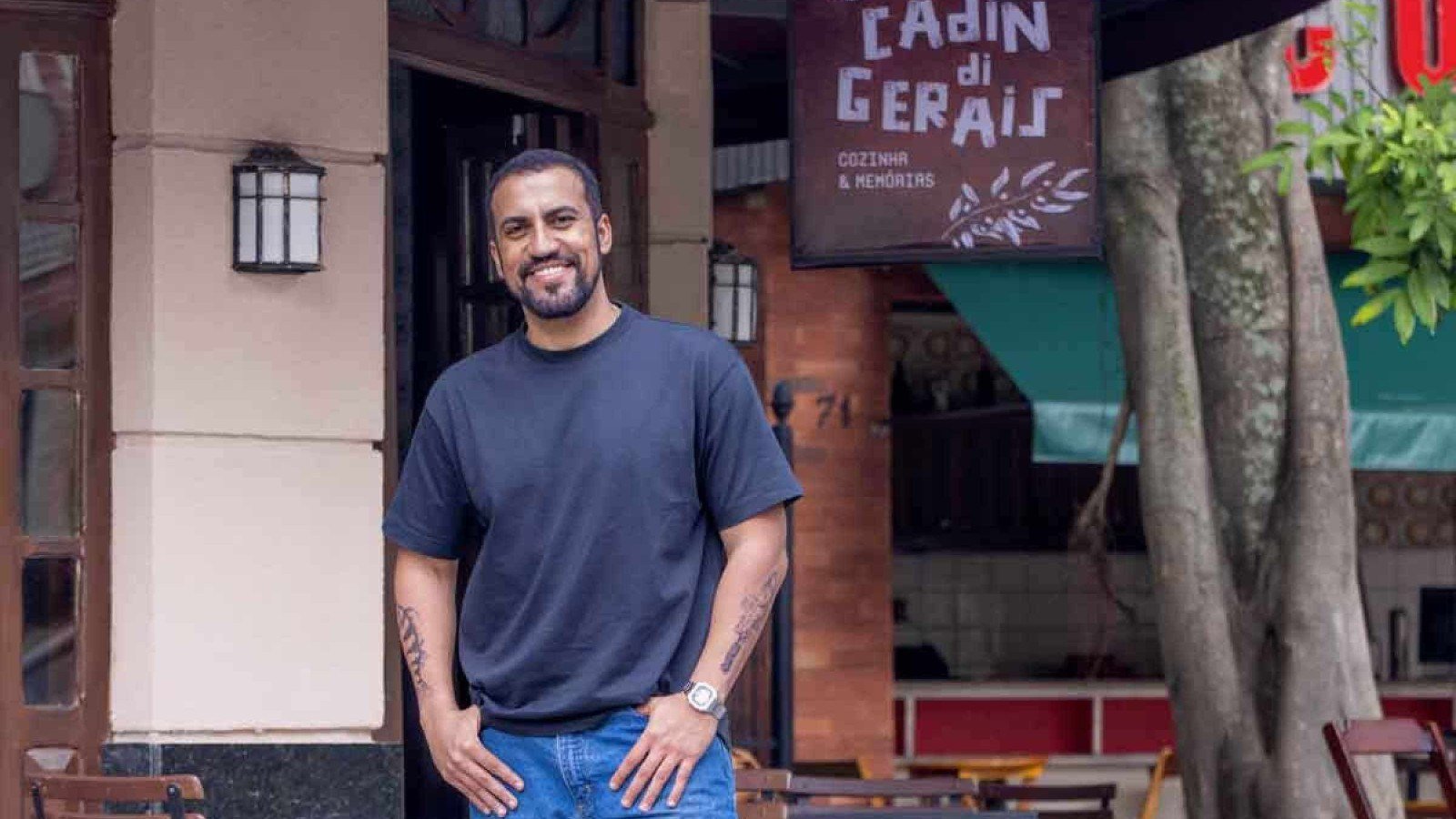Ator Ricardo Teodoro usa blusa e cal&ccedil;a azuis e sorri para a c&acirc;mera, em frente ao restaurante onde ele roda cenas da novela Quem ama cuida