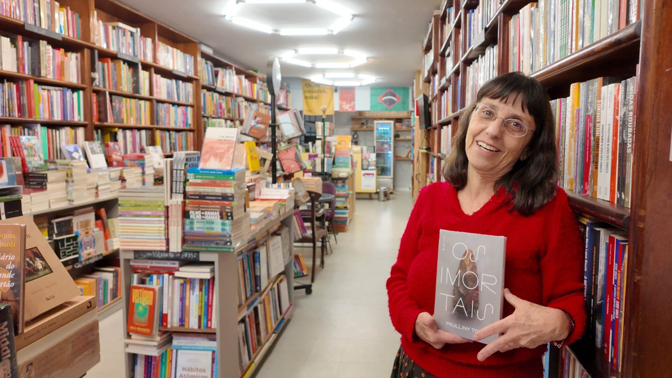 Simone Pessoa, livreira da Livraria Jenipapo, segurando sua recomenda&ccedil;&atilde;o "Os imortais", de Paulliny Tort