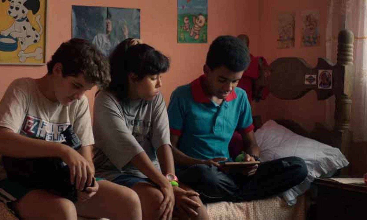 Atores mirins Matheus Sampaio, Tatiana Costa e Daniel Victor est&atilde;o sentados na cama conversando em cena do filme O &uacute;ltimo epis&oacute;dio