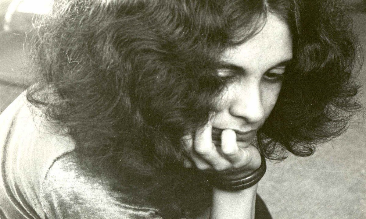 A jovem Gal Costa, com fartos cabelos encaracolados, tem o queixo nas m&atilde;os e olha para baixo