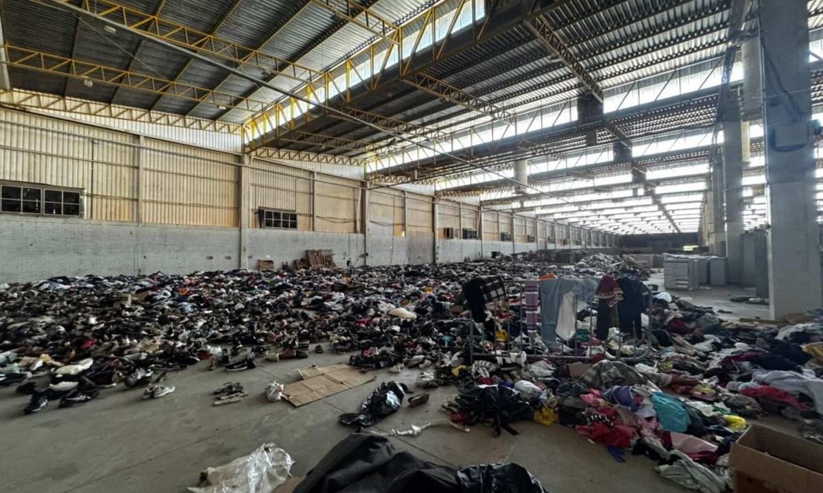 O local está repleto de roupas empilhadas, sacos fechados e peças espalhadas pelo chão - (crédito: Reprodução/Soninha da Policlínica )