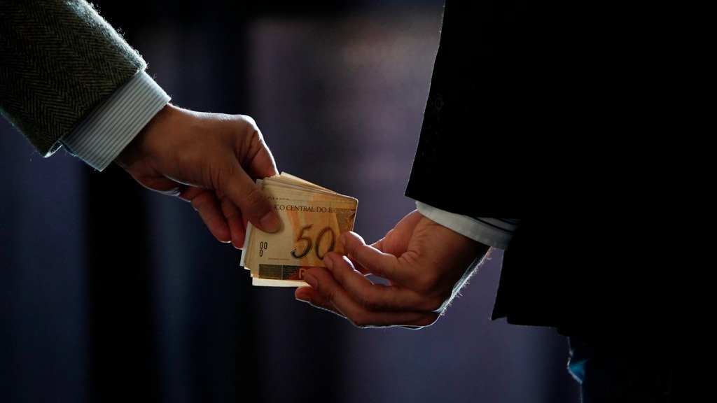 A troca de dinheiro em m&atilde;os, ilustrando propina, reflete a estagna&ccedil;&atilde;o do Brasil no ranking de corrup&ccedil;&atilde;o da Transpar&ecirc;ncia Internacional -  (crédito: Reprodu&ccedil;&atilde;o)