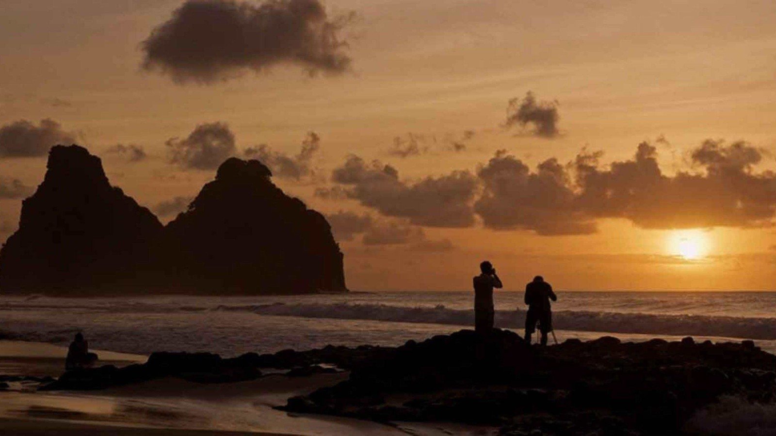 Jayme Matarazzo e Luciano Candisani posicionam c&acirc;meras em trip&eacute;s. Ao fundo, v&ecirc;-se o belo por do sol refletindo-se no mar de Fernando de Noronha