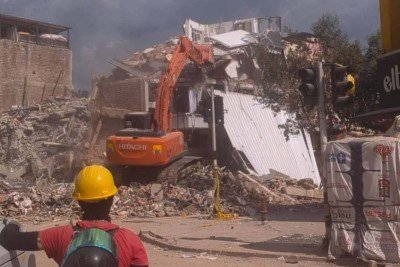 Voluntário observa enquanto máquina derruba prédio vizinho a uma edificação colapsada na qual, até dois dias antes, procuravam-se sobreviventes em Pereira, na Colômbia  -  (crédito: Phillippe Watanabe/Folhapress)