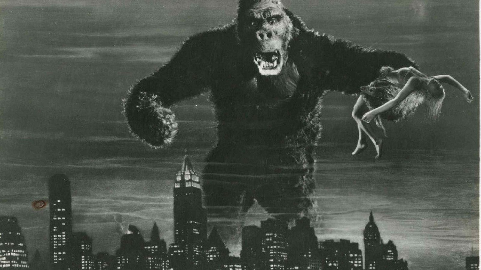 Enorme gorila segura mulher com uma das patas. Eles est&atilde;o sobre pr&eacute;dios da metr&oacute;pole em cena do filme King Kong