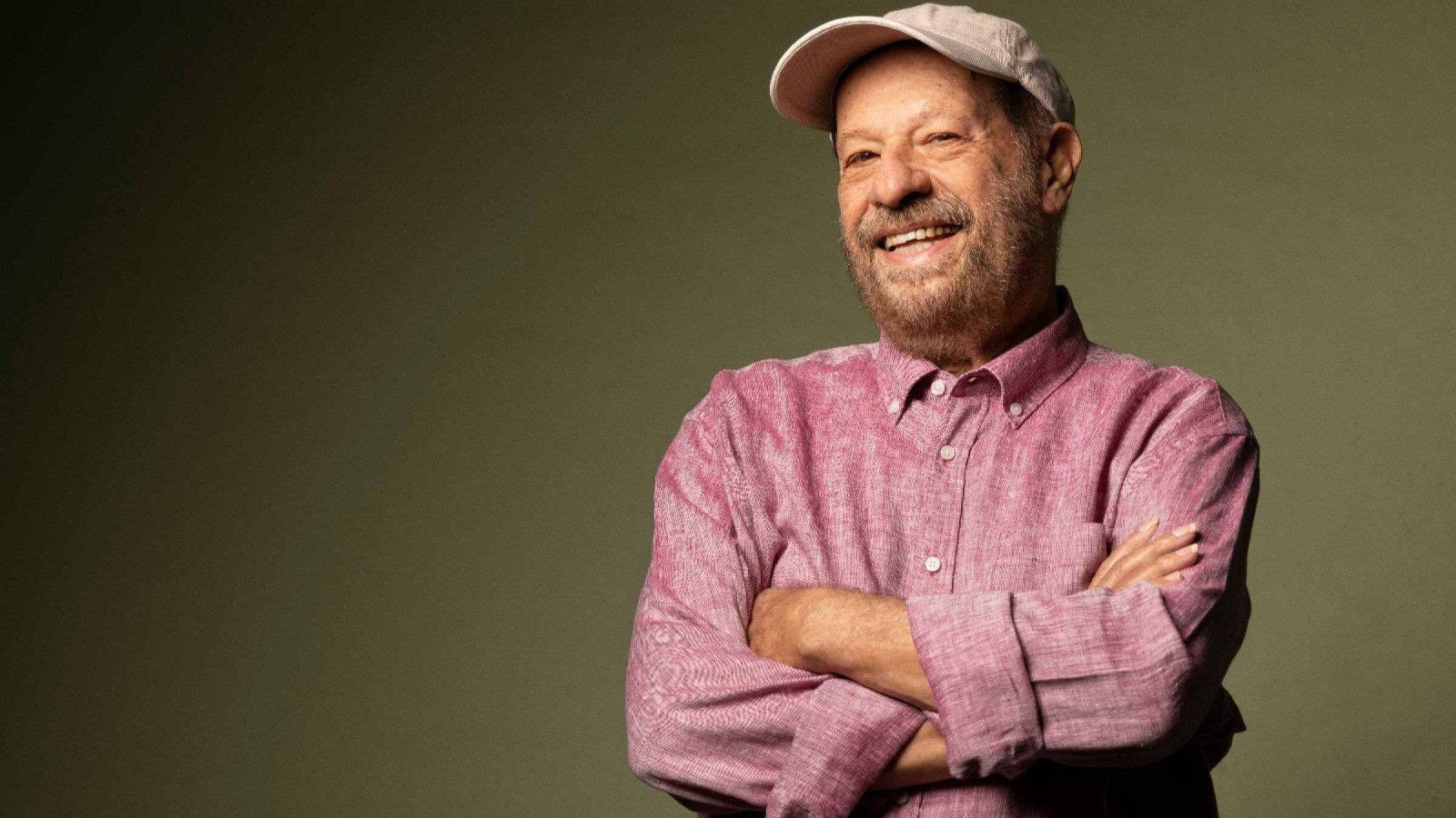 Jo&atilde;o Bosco veste camisa rosa e sorri, com os bra&ccedil;os cruzados