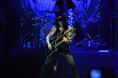 Sua identidade visual, marcada pela cartola, cabelos longos e óculos escuros, se tornou tão reconhecida quanto seu estilo na guitarra. Slash ganhou fama mundial como integrante do Guns N' Roses, grupo que ajudou a transformar o rock do fim dos anos 1980. -  (crédito: Flickr - Agencia de Noticias ANDES)