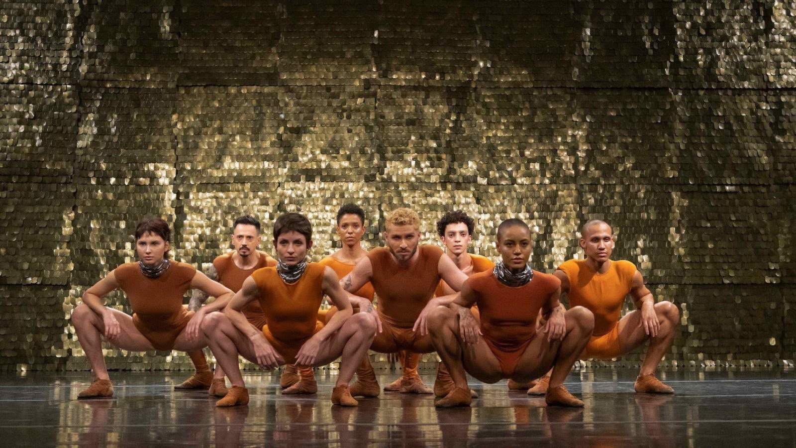 Bailarinos do Grupo Corpo est&atilde;o de frente para a c&acirc;mera, agachados no ch&atilde;o, em cena da coreografia Piracema