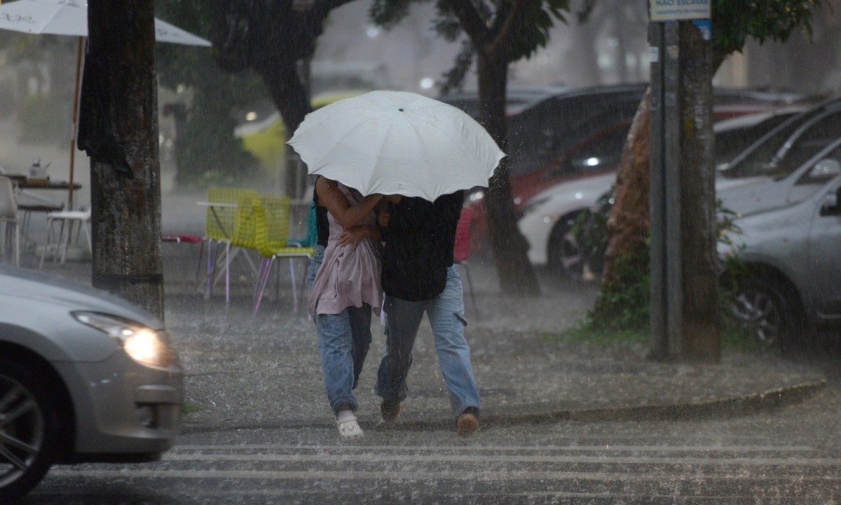 Pessoas se protegem da chuva em rua de Belo Horizonte. A capital mineira pode ter pancadas de chuva e trovoadas isoladas durante a tarde - (crédito: Tulio Santos/EM/D.A. Press)