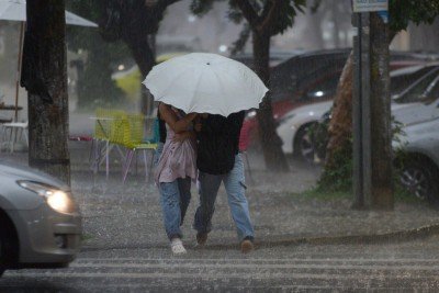 Pessoas se protegem da chuva em rua de Belo Horizonte. A capital mineira pode ter pancadas de chuva e trovoadas isoladas durante a tarde -  (crédito: Tulio Santos/EM/D.A. Press)
