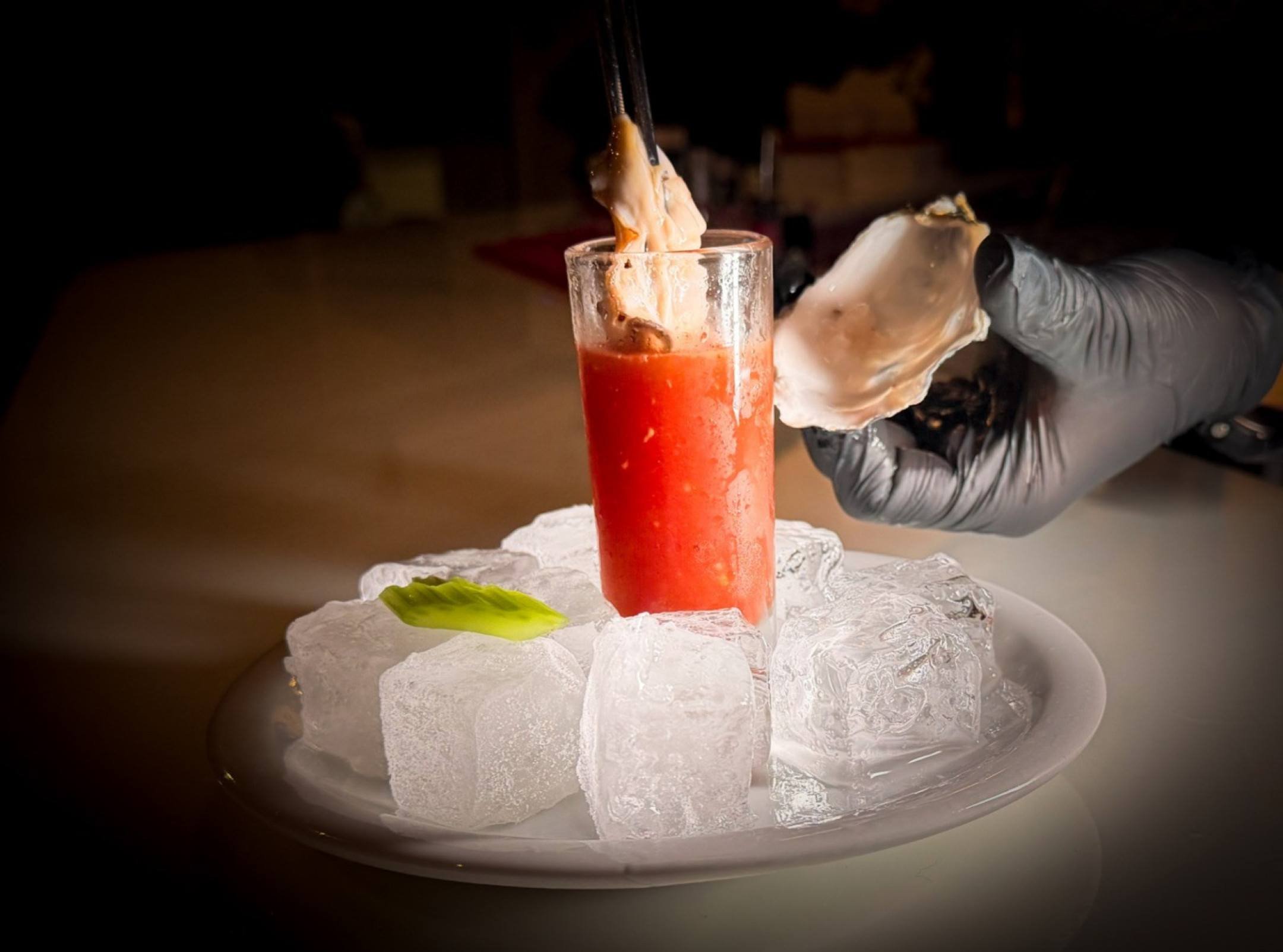 O coquetel vira um shot, servido com ostra fresca, no Banqueta: o fruto do mar leva mais umami para a bebida 
