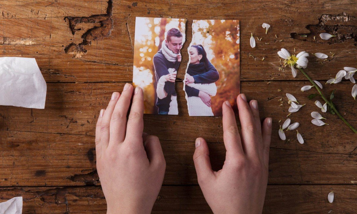 Unrecognizable woman holding torn picture of couple in love. Ended relationship. Crying.Valentines day composition. Studio shot on brown wooden background.
- (crédito: Wemystic)
