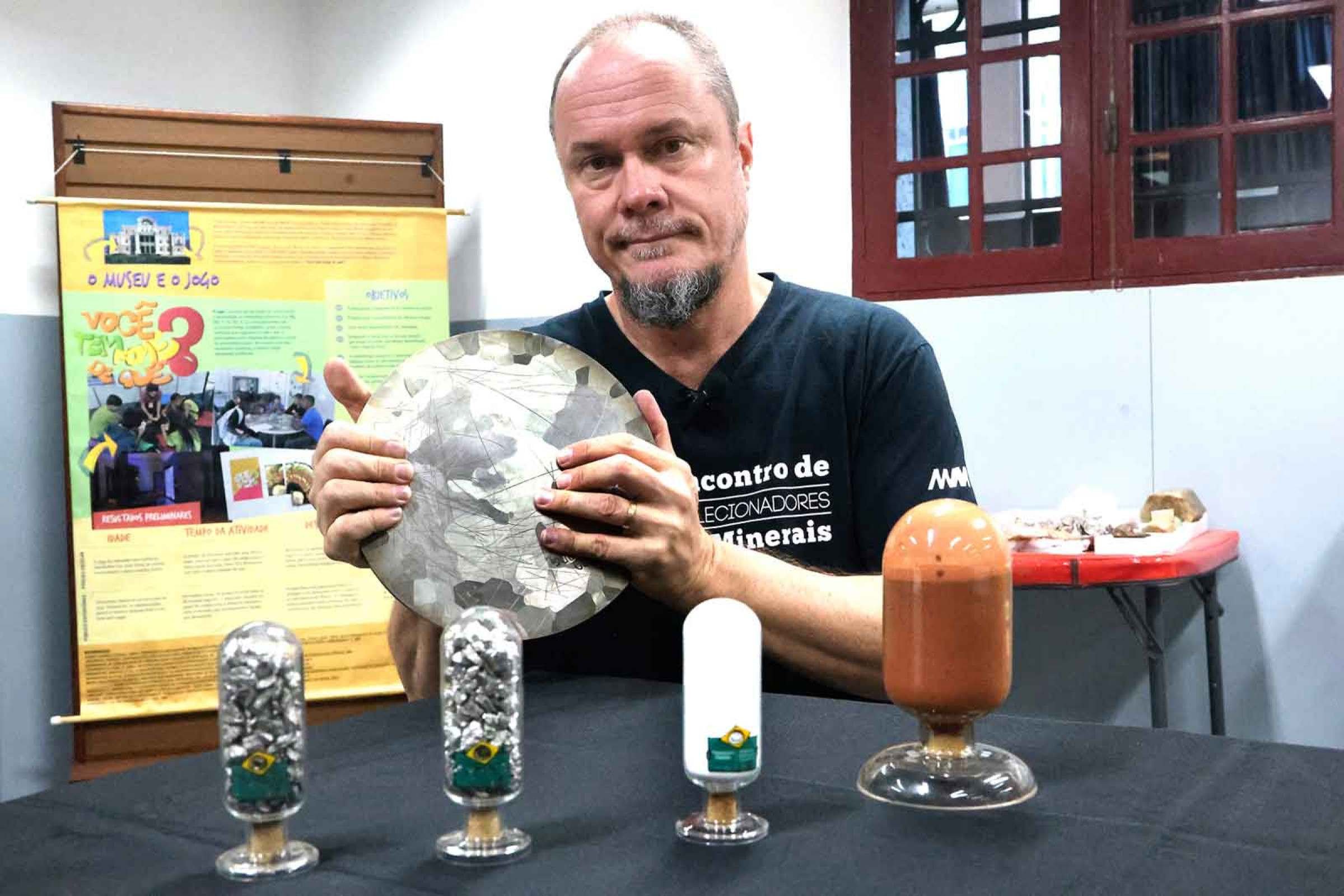 Qu&iacute;mico e pesquisador do Museu das Minas e do Metal (Museu MM Gerdau), Luciano Faria  segura um disco de ni&oacute;bio, tendo &agrave; sua frente amostras de &oacute;xido de ni&oacute;bio e pirocloro