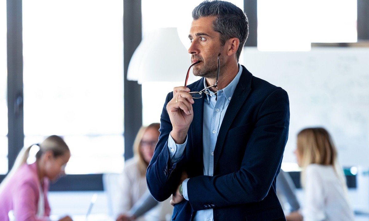Shot of handsome businessman looking to sideways while his colleagues are working on coworking place.
- (crédito: Lifestock)