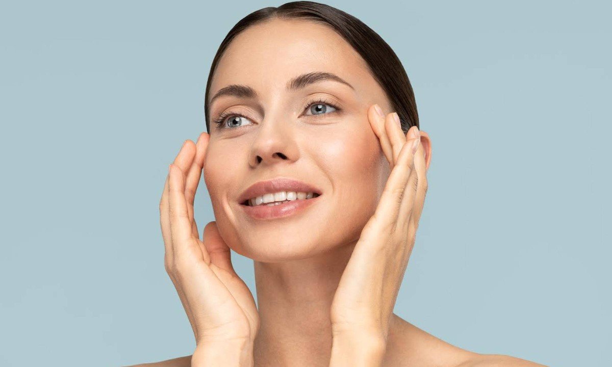 Studio portrait of young woman with natural makeup, combed hair, touching well-groomed pure skin on face, isolated on blue background. Beauty, facelift, anti-aging cosmetic procedure. Banner.
- (crédito: DINO)