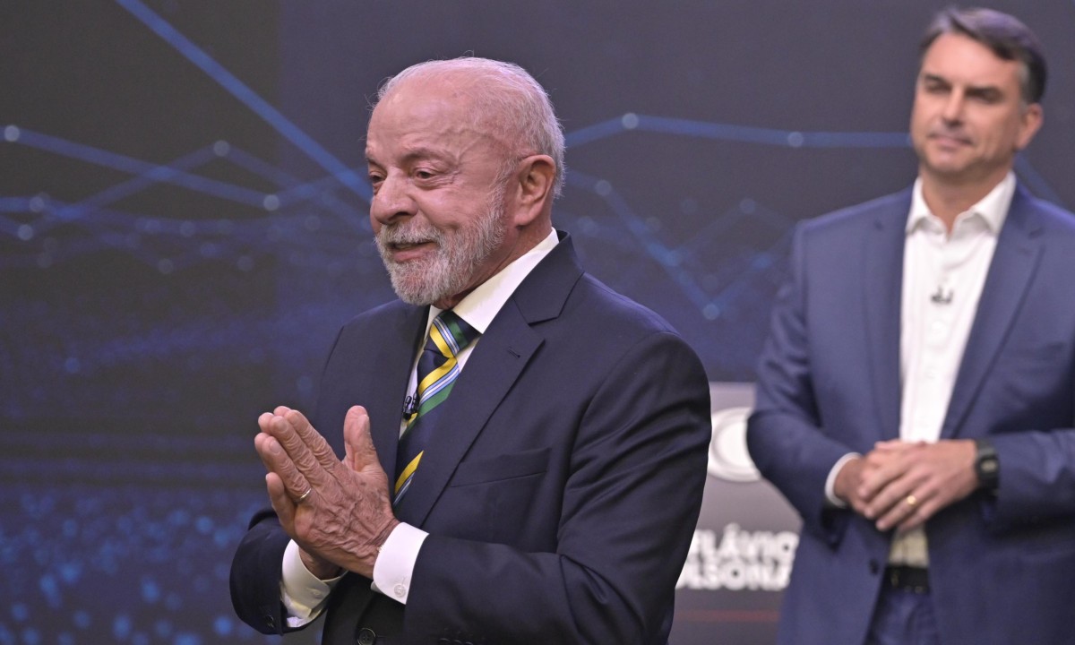 Flávio Bolsonaro (ao fundo) em estratégia para gerar imagens de confronto atrás de Lula durante debate presidencial na Band - (crédito: Renato Pizzutto/Band)