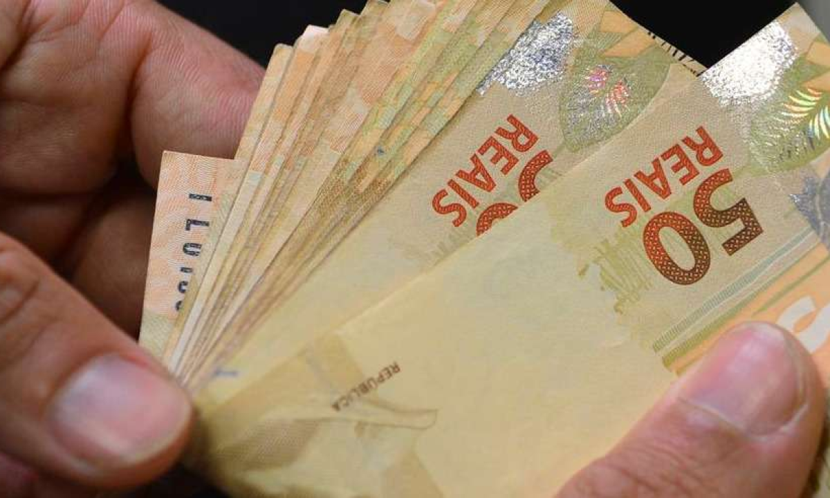 Imagem de uma pessoa manuseando cédulas de dinheiro -  (crédito: Marcello Casal Jr/Agência Brasil)