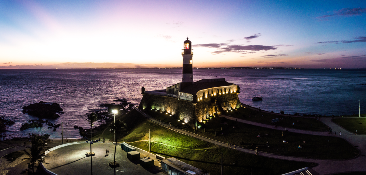 Encante-se com o pôr do Sol no Farol da Barra, em Salvador. Local onde todo de mundo se encontra, seja para curtir uma roda de capoeira, seja para saborear um acarajé