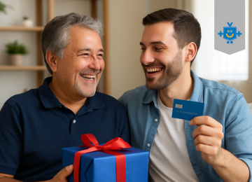 Pai e filho sorrindo no sofá com um cartão de crédito e uma caixa de presente, em clima de presente de Dia dos Pais.
 -  (crédito: Reprodução Educando seu Bolso )