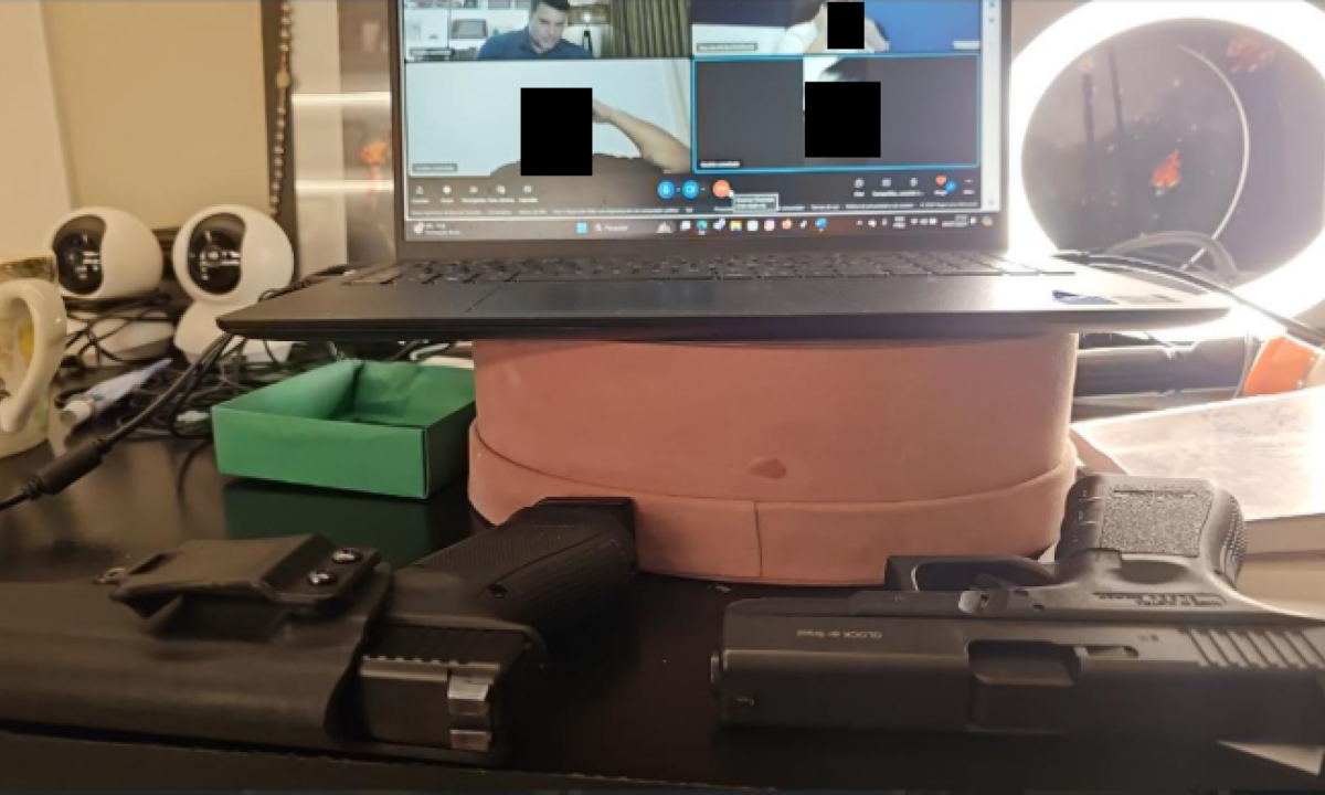 Duas pistolas pretas em frente ao um notebook usado por Renê da Silva Nogueira Júnior, réu pela morte do gari Laudemir de Souza Feranandes