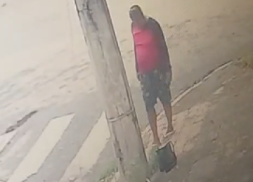 Imagens de câmeras de segurança mostram o homem caminhando pela via e, ao notar a bolsa, pegando o material e deixando o local -  (crédito: PMMG/Reprodução)