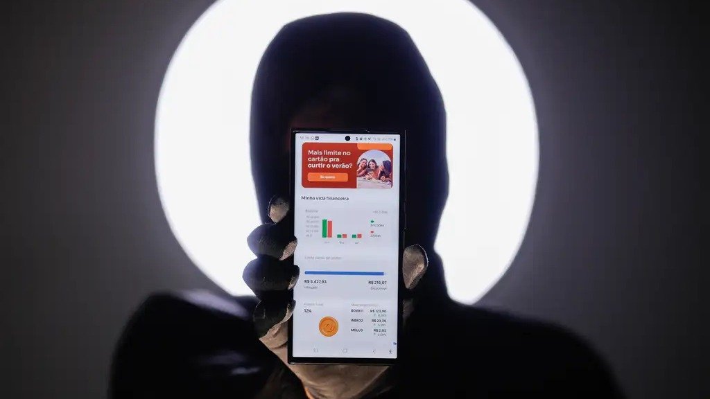 A figura an&ocirc;nima segurando um smartphone com aplicativo financeiro ilustra o perigo invis&iacute;vel dos golpes virtuais e da engenharia social -  (crédito: Jo&eacute;dson Alves/Ag&ecirc;ncia Brasil)