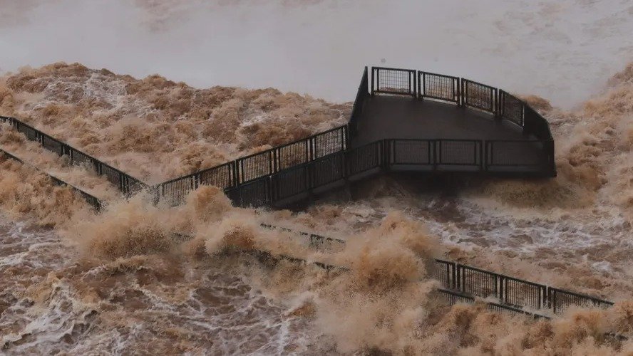 A passarela das Cataratas do Igua&ccedil;u resiste &agrave; for&ccedil;a de uma cheia, evidenciando a robustez de sua constru&ccedil;&atilde;o ancorada no leito rochoso do rio. -  (crédito: Christian Rizzi/AFP)
