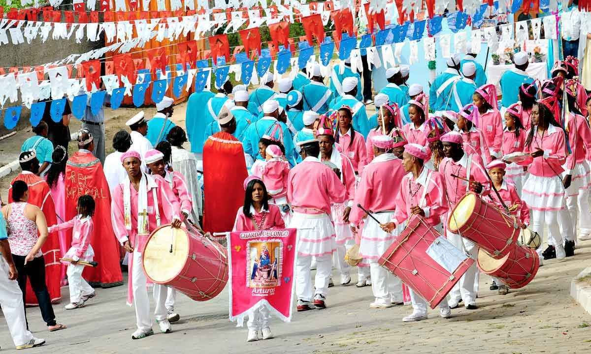 vestindo roupas solenes nos tons de azul e rosa e carregando instrumentos e bandeiras, Integrantes da Comunidade dos Arturos desfilam em frente à igreja Nossa Senhora do Rosário
-Gladyston Rodrigues - 13/05/2012