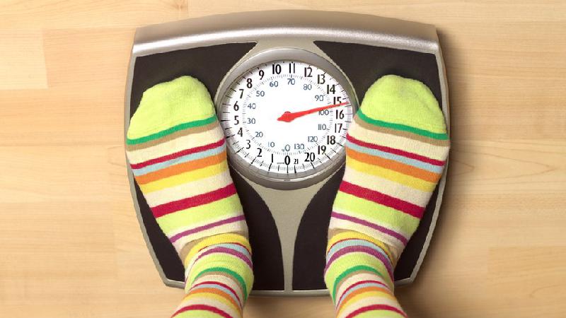 Pés de alguém com meia listrada colorida se pesando em uma balança -  (crédito: Getty Images)