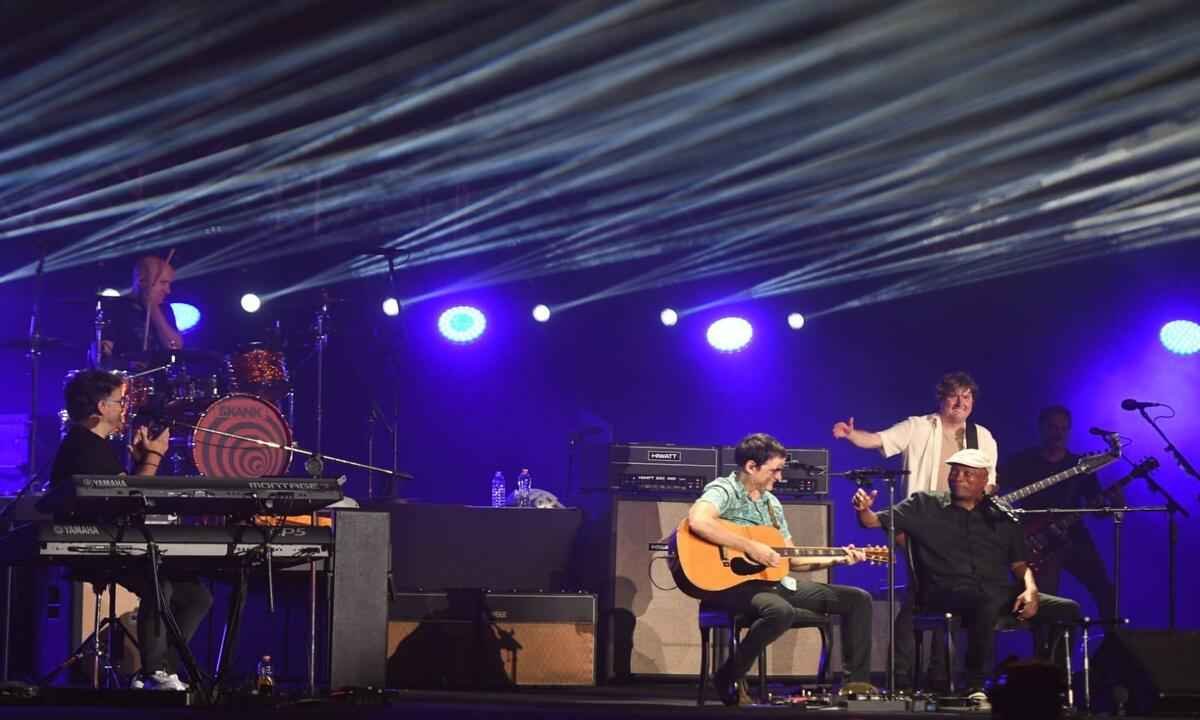 Milton Nascimento, sentado, e os quatro integrantes do Skank, no palco